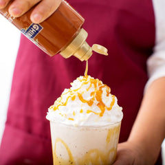 Ghirardelli salsa de caramelo vertida sobre helado para un topping atractivo