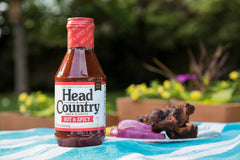 Head Country pincelando costillas en parrilla para sabor intenso