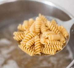 Comparación de tamaño del fusilli Jovial Einkorn junto a una mano para apreciar la escala de la pasta
