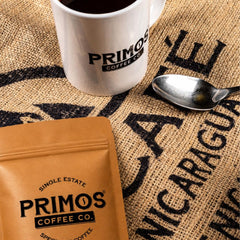 Primos Coffee Co. bolsa junto a taza para comparar tamaño y porciones por bolsa