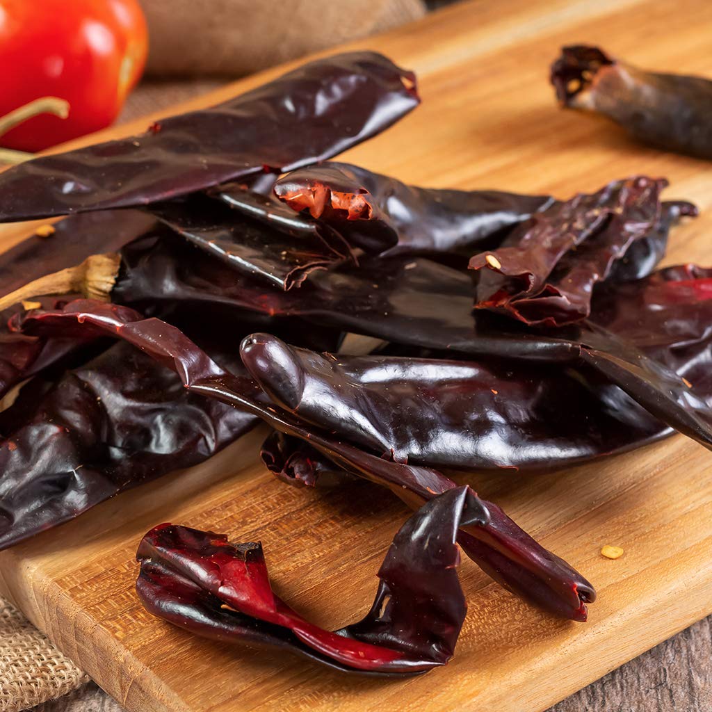 1400S SPICES mano sosteniendo un chile guajillo para mostrar tamaño y facilidad de uso