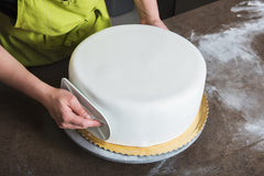 Bakerpan manos estirando fondant listo para cubrir pastel con acabado liso