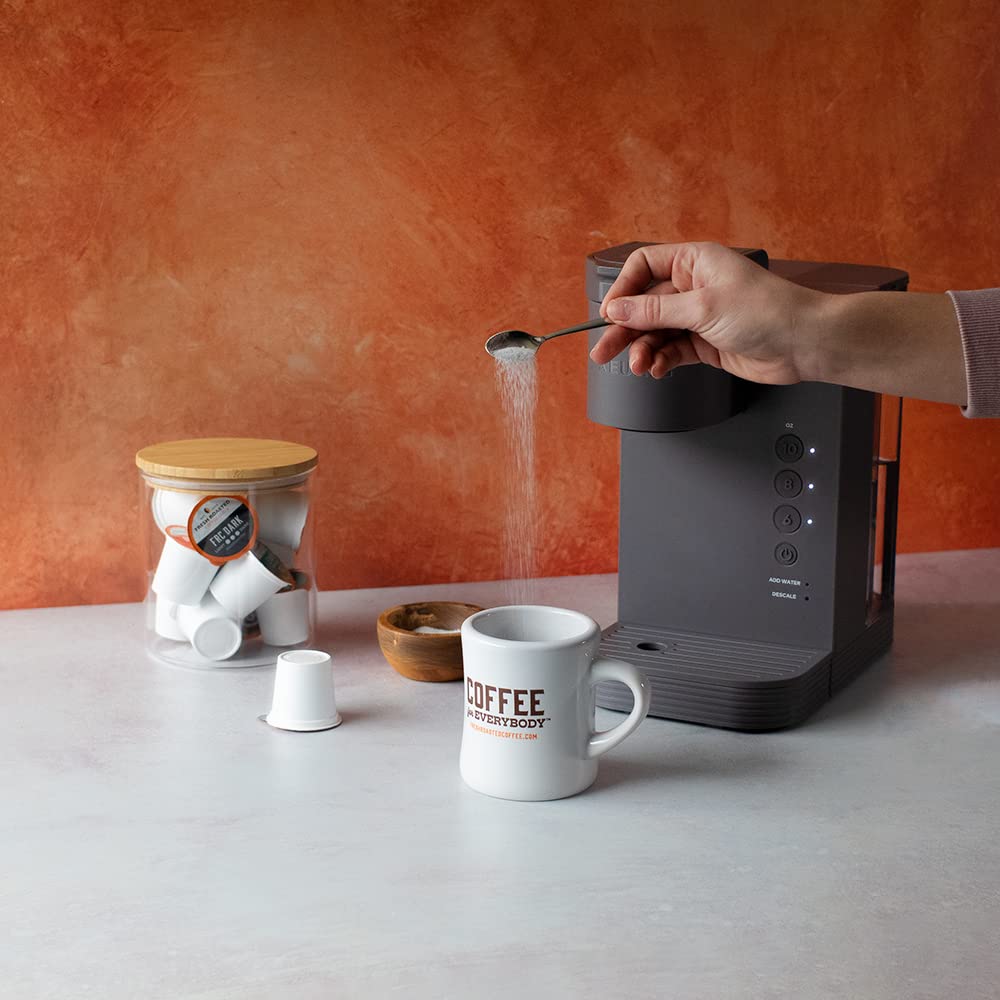Fresh Roasted Coffee cápsula junto a taza para escala, tamaño práctico y ahorro