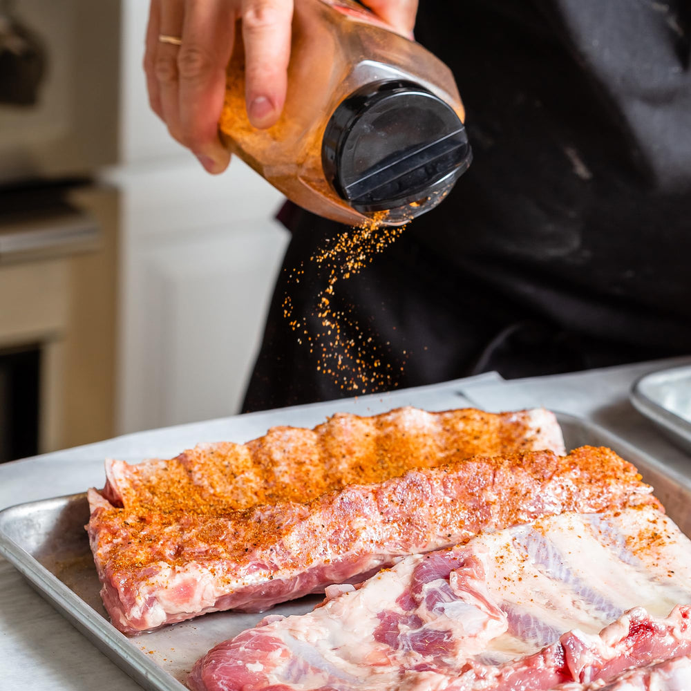 GranAroma sazonador espolvoreado sobre carne en parrilla para sabor ahumado intenso