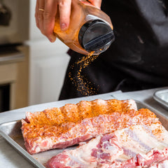 GranAroma sazonador espolvoreado sobre carne en parrilla para sabor ahumado intenso