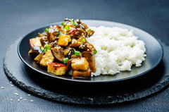 Chef vertiendo Lee Kum Kee Premium Soy Sauce sobre salteado, mejora sabor al instante