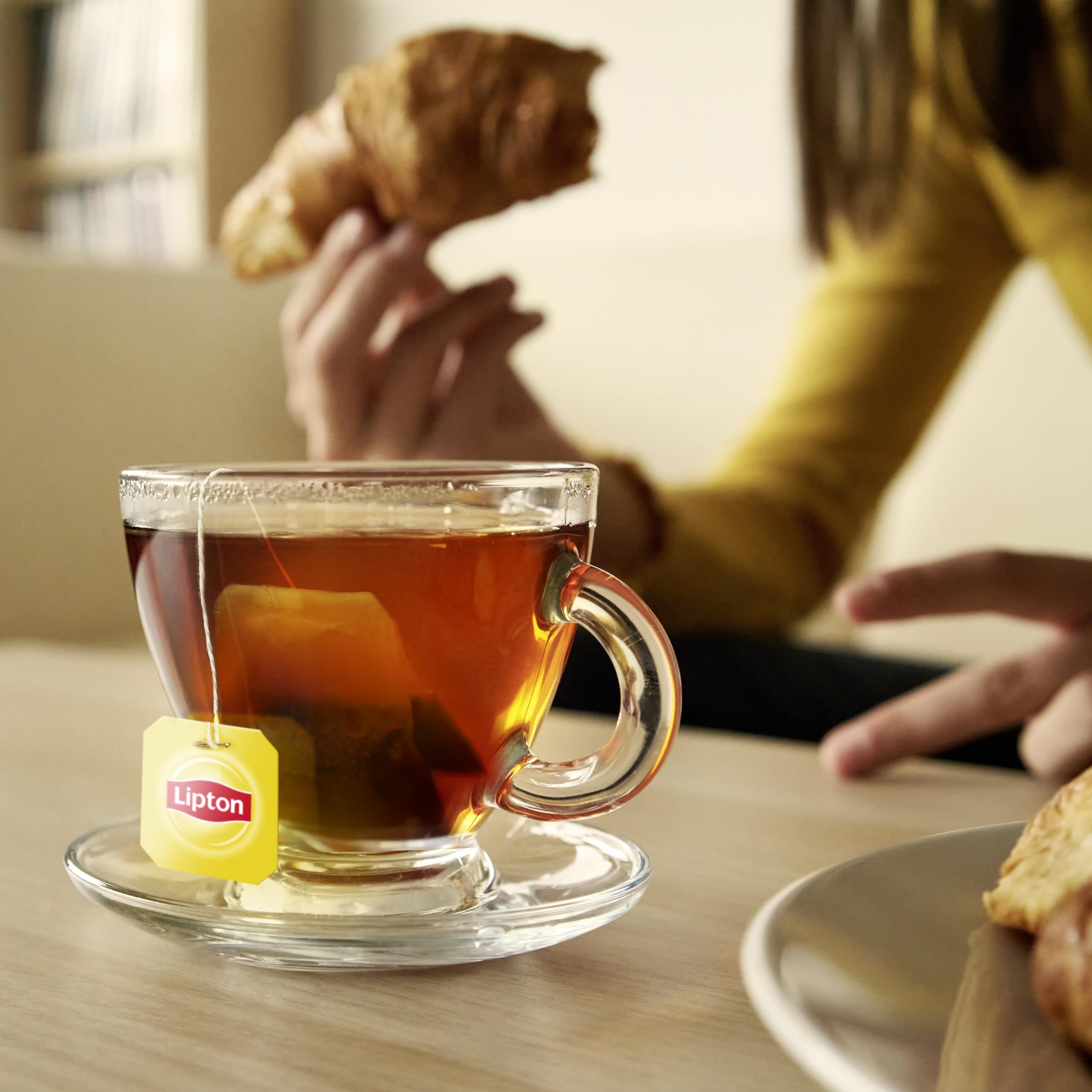 Manos vertiendo té Lipton en vaso, preparación rápida en casa u oficina