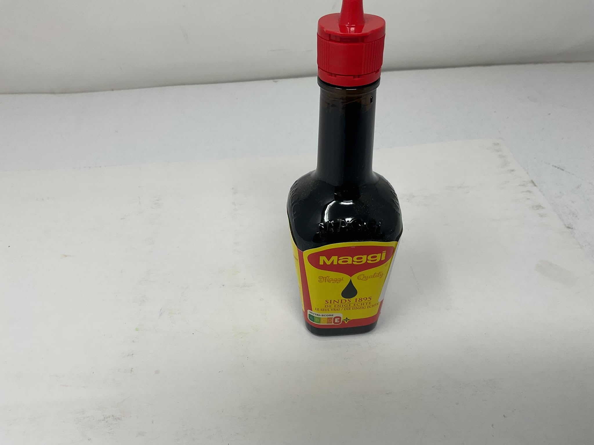 Botella Maggi junto a una cuchara para comparar tamaño y porción