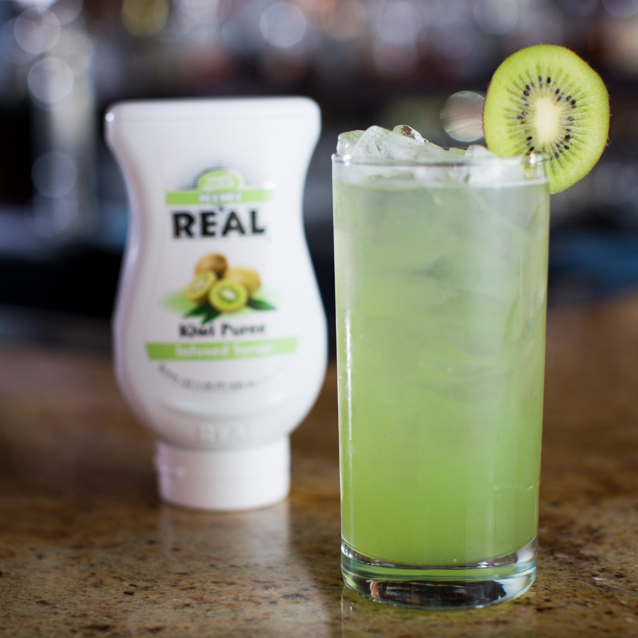 Reàl Infused Exotics botella junto a mano para mostrar escala y volumen práctico