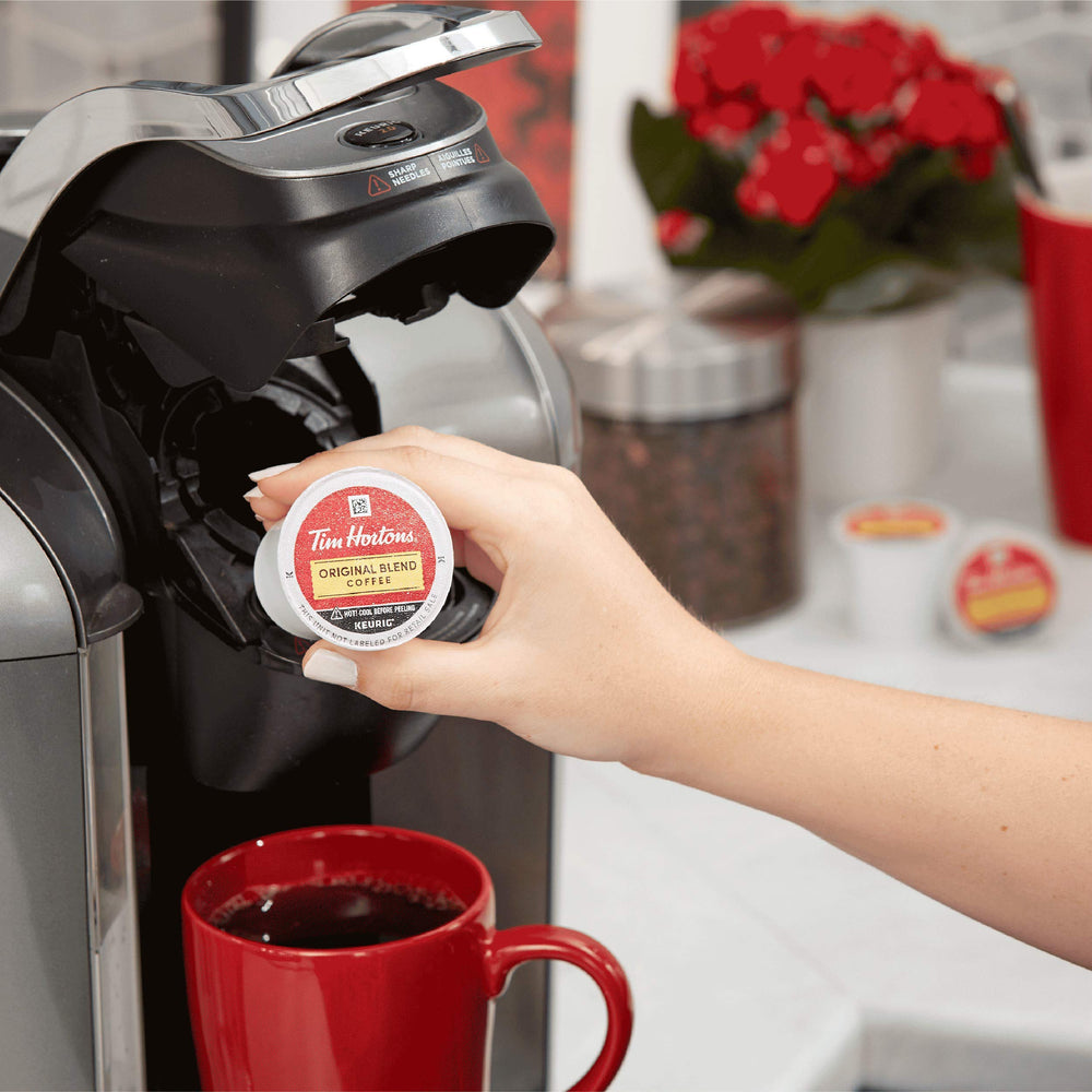 Persona vaciando posos de cápsula Tim Hortons en un contenedor de reciclaje, fomenta sostenibilidad local