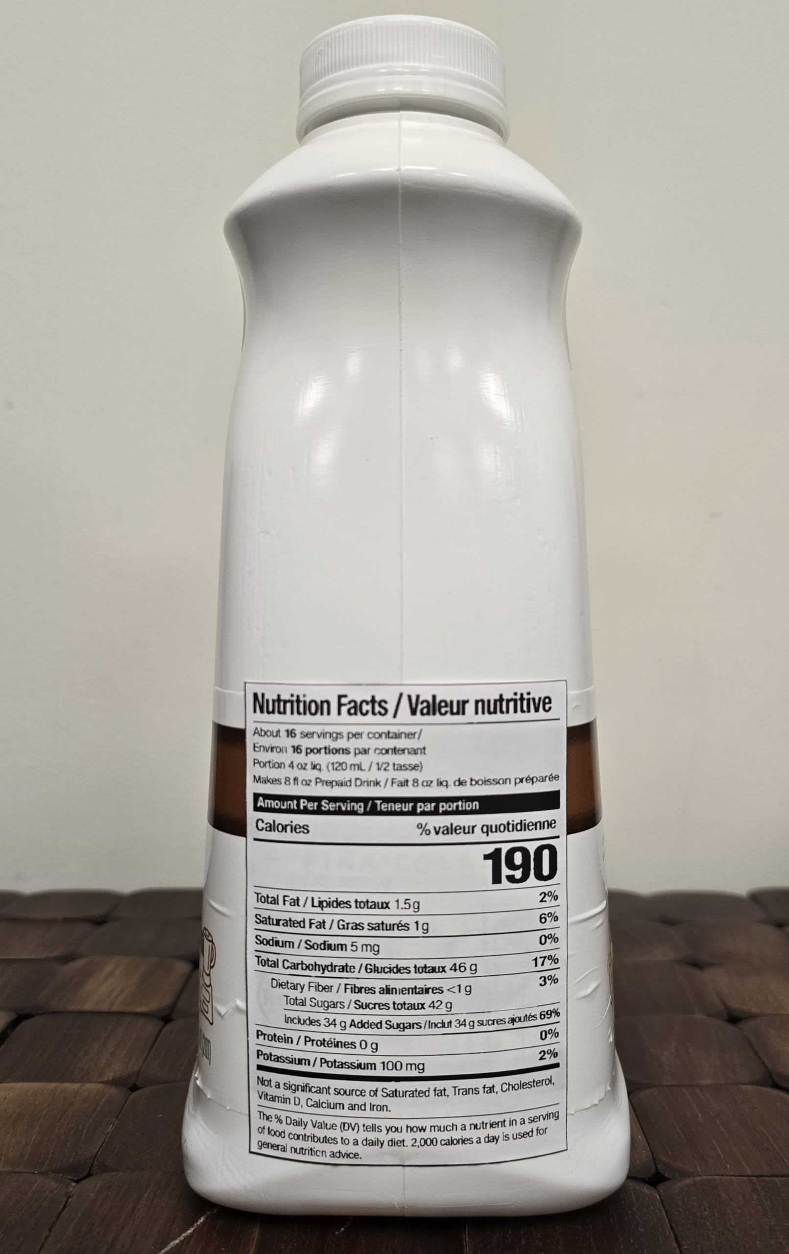 Torani envase 64 fl oz en manos, demostrando rendimiento por porción